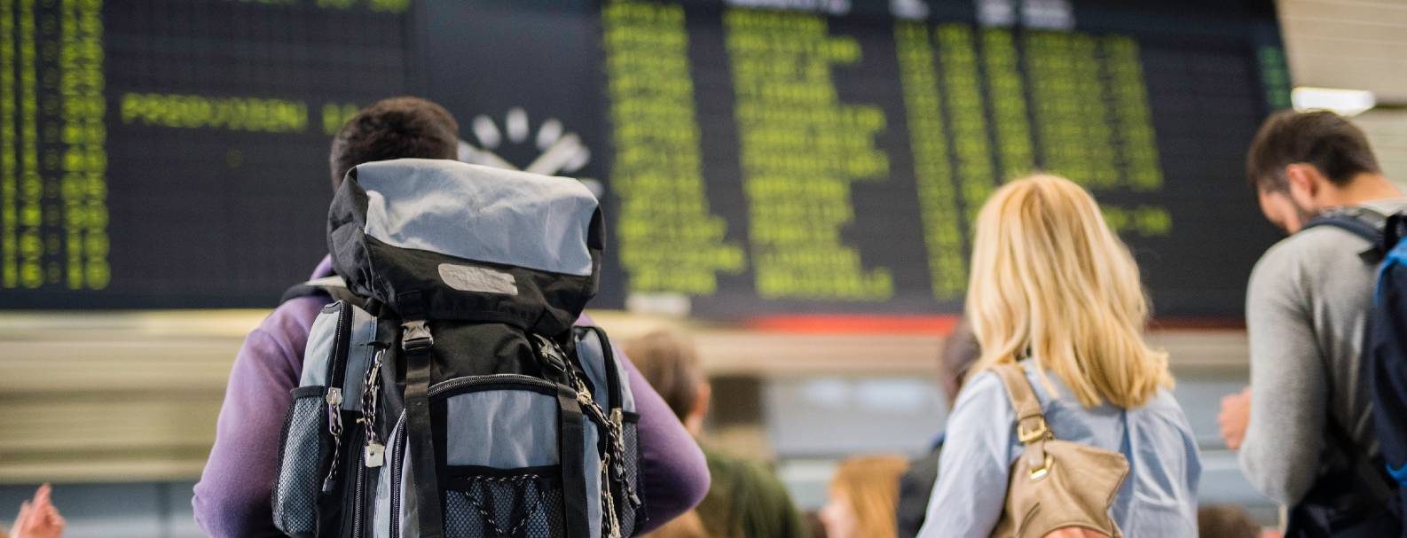 Image de voyageurs regardant le tableau montant l'état des vols à l'aéroport